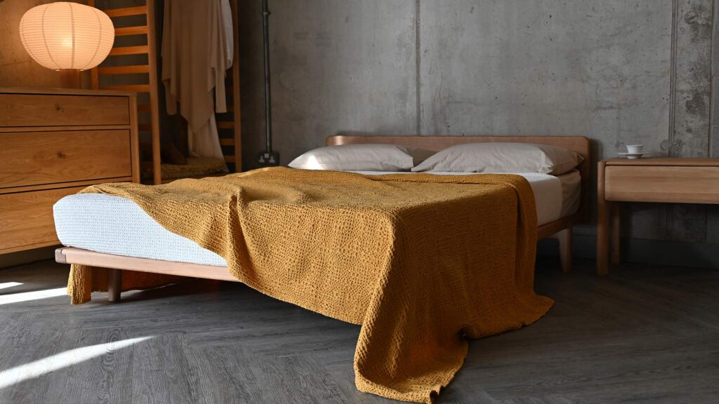 A mustard yellow waffle textured bedspread on a solid cherry Osaka bed base.