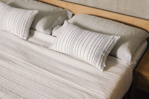 white kantha bedspread with striped cushions