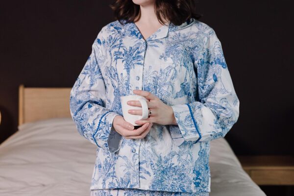 model wearing blue and white jungle print pyjamas holding a mug.